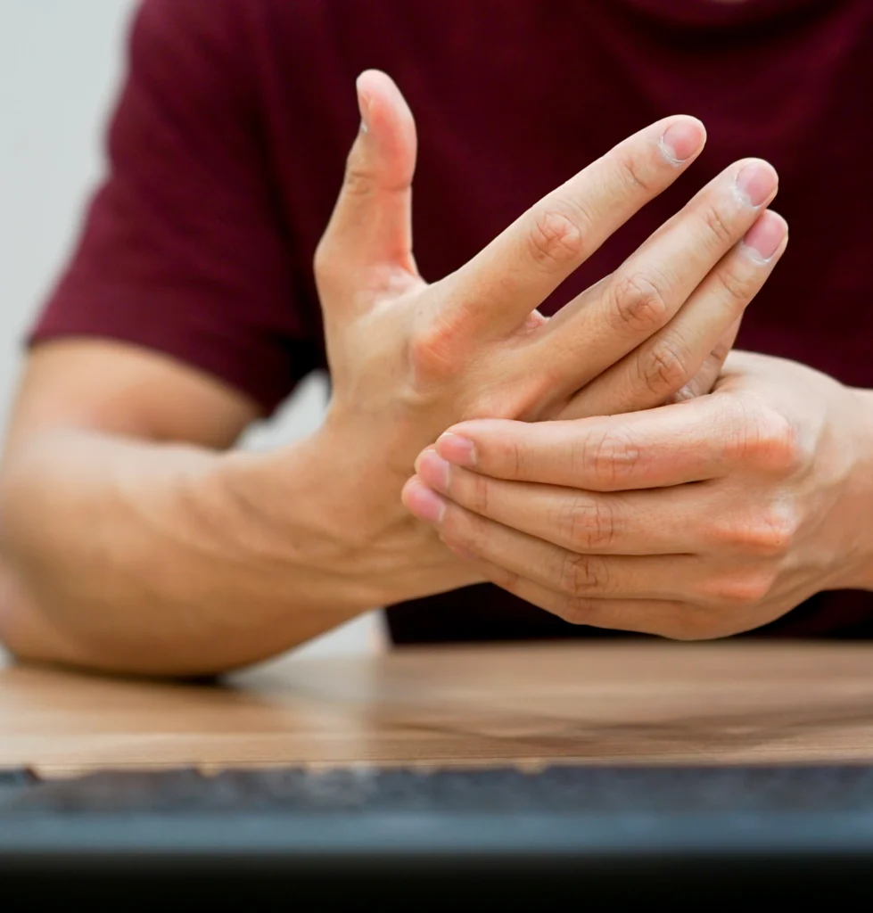 Man at a desk holding his wrist in pain, a common sign of carpal tunnel syndrome