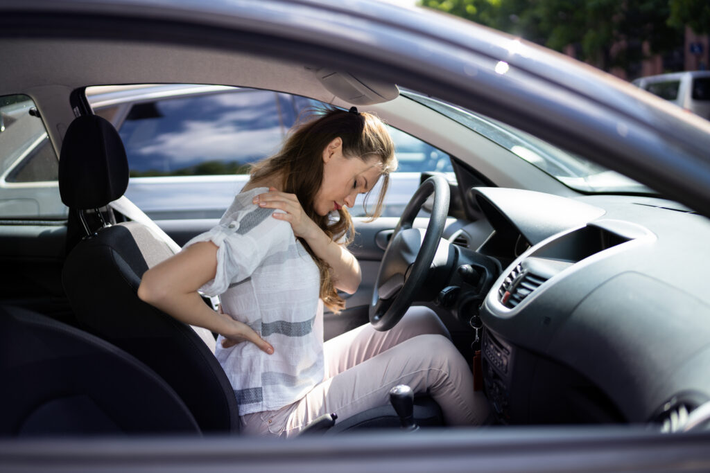 Person holding their neck in pain after a car accident, showing signs of whiplash injury
